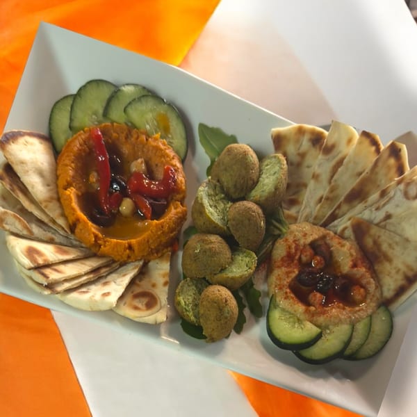 Romo's Mediterranean Grill platter with two types of hummus, falafel, pita bread, and cucumber slices.