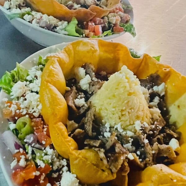 Two Romo's Mediterranean Grill gyro bowls with meat, rice, feta, and fresh vegetables.